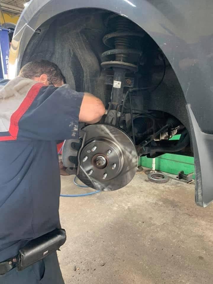 Finish Line technician inspecting a brake rotor and caliper in Livonia, MI