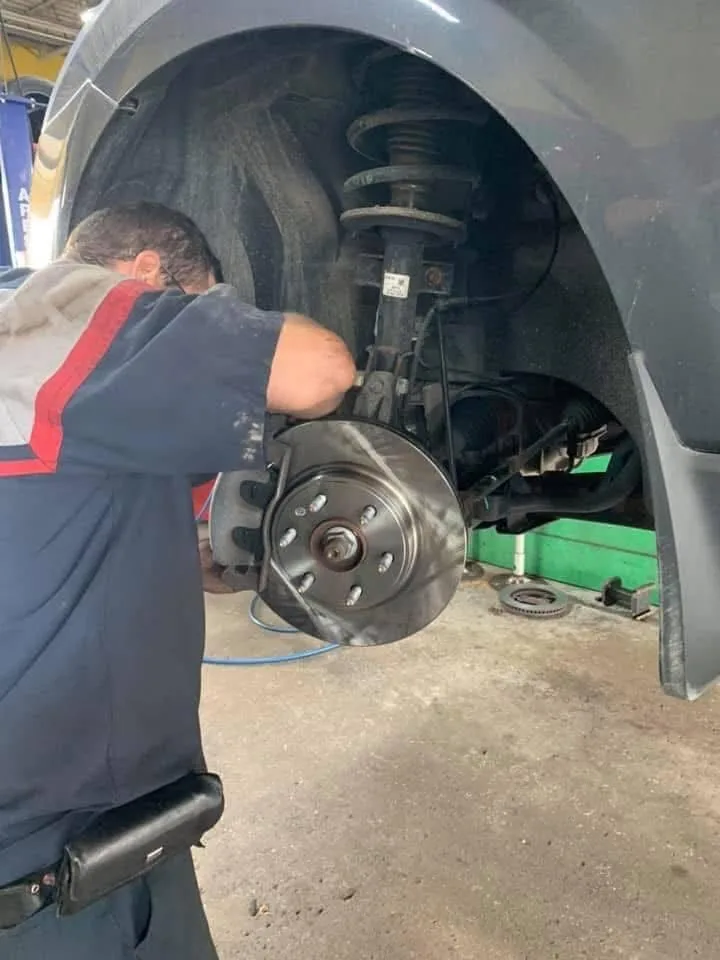 Finish Line technician inspecting a brake rotor and caliper in Livonia, MI